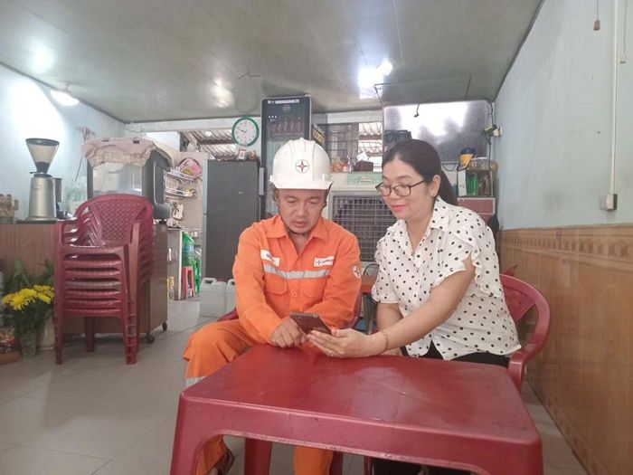 Cán bộ ngành điện hướng dẫn chị Nguyễn Thị Kim Giang (trú tại phường Hòa Cường, Đà Nẵng) dùng ứng dụng EVN CSKH. Ảnh: Văn Giáp/Bnews/TTXVN