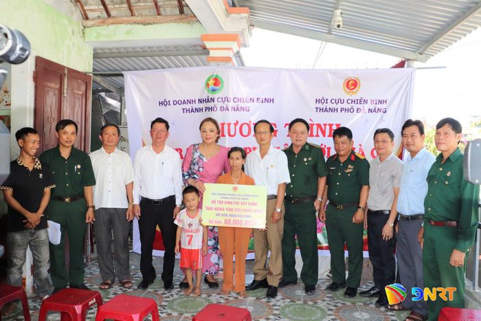 Phó Chủ tịch Hội Cựu chiến binh thành phố Huỳnh Bá Thành (thứ 6 bên phải qua) và Phó Chủ tịch Hội Doanh nhân Cựu chiến binh thành phố Hồ Thị Thắng (thứ 5 bên trái qua) trao tiền hỗ trợ cho gia đình cựu chiến binh Đoàn Anh Dũng, xã Thăng An. Ảnh: XUÂN PHƯỚC