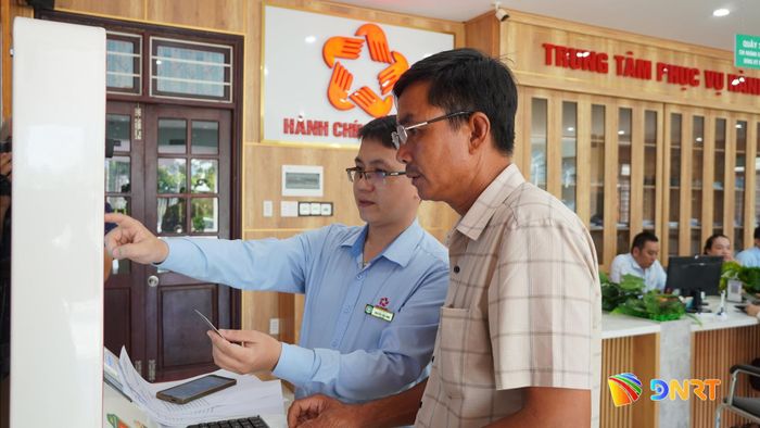 Ông Trần Đình Phát được hướng dẫn thực hiện thủ tục hành chính trên kiosk thông minh. Ảnh: DIỄM LỆ