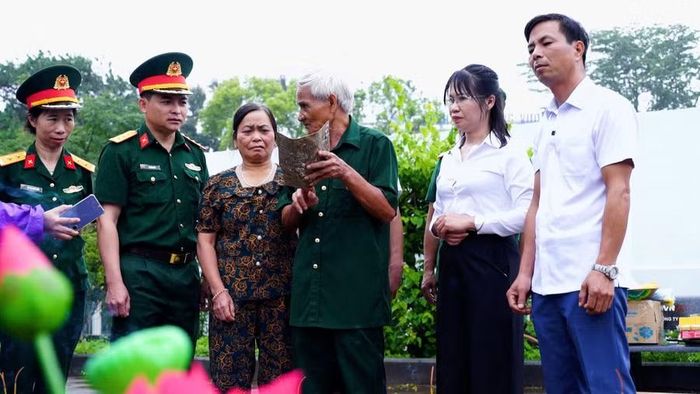 Cựu chiến binh Lê Văn Thuân (thứ 3 từ phải sang) - người trực tiếp chôn cất và khắc thông tin lên tấm nhôm - xem lại di vật sau gần 50 năm. Ảnh: Minh Trung