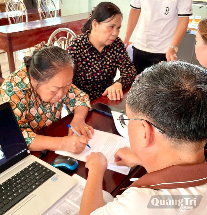 Bà Trần Thị Lan đang được Tổ phục vụ hành chính công lưu động hướng dẫn làm thủ tục hành chính - Ảnh: S.H