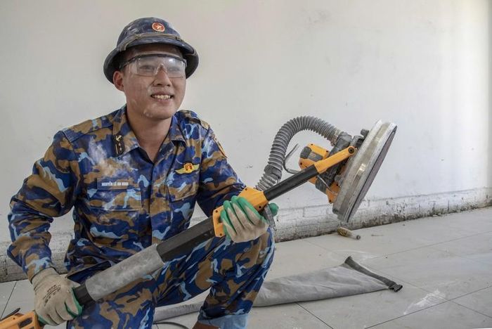 Trung úy Nguyễn Lê An Ninh với khuôn mặt lấm lem vì tham gia đánh xả ma-tít và sơn tường các phòng học. Ảnh: Lê Văn Chương