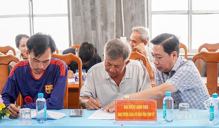 Đồng chí Đỗ Chí Công, Trưởng phòng Thông tin - Tổng hợp, Ban Tuyên giáo Tỉnh uỷ Cà Mau (bìa phải), hỗ trợ người dân ghi phiếu điều tra.