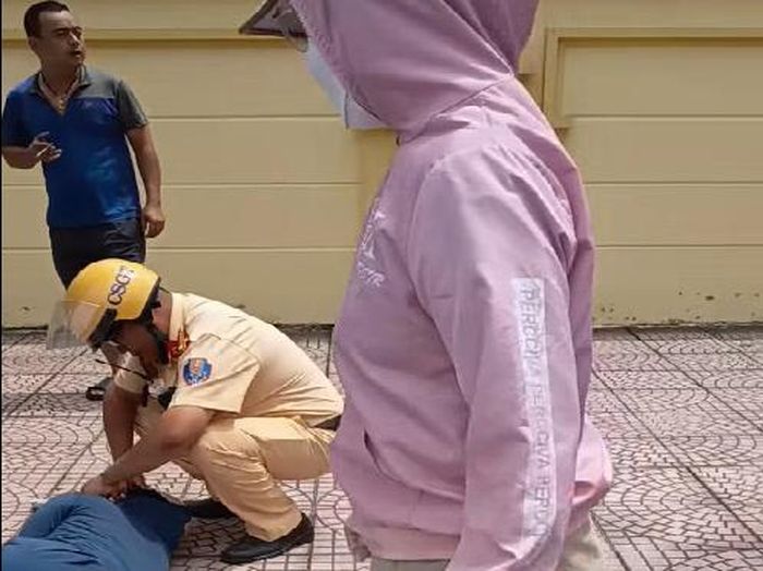 Trung tá Nguyễn Đức Thành thực hiện sơ cứu tại chỗ khi chị Tô Thị Thủy bị đột quỵ. Ảnh: CA.
