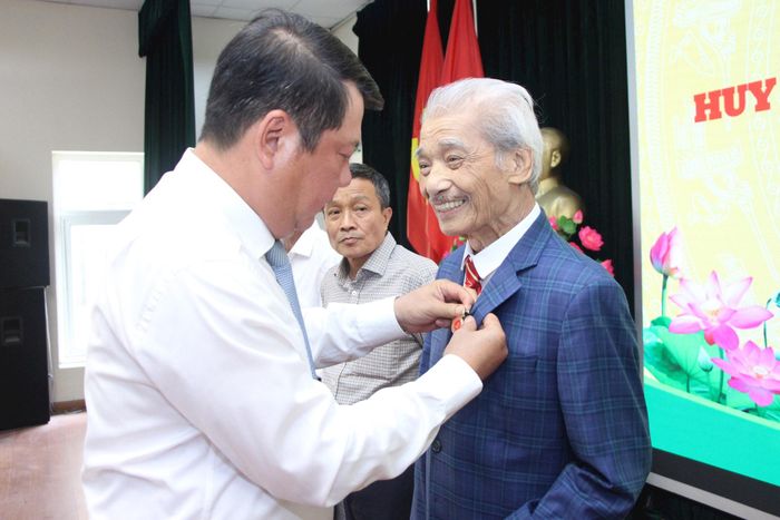 Bí thư Đảng ủy, Chủ tịch HĐND phường Giảng Võ Tống Học Nghĩa trao Huy hiệu 35 năm tuổi Đảng cho NSND Trần Hiếu. Ảnh: TT