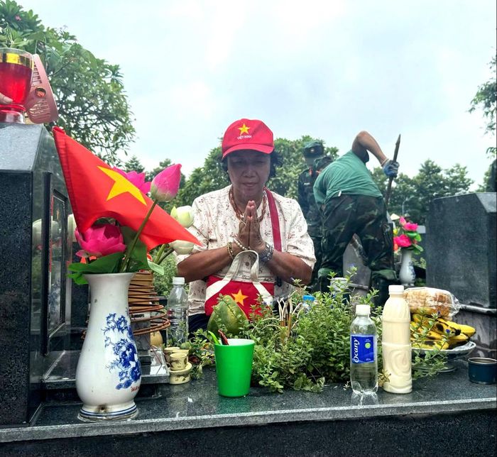 Bà Trương Thị Bình (74 tuổi, trú tại phố Hoàng Đạo Thành, Hà Nội) cẩn trọng thắp từng nén tâm hương lên phần mộ người chú ruột - liệt sĩ Trương Nghê tại Nghĩa trang liệt sĩ Mai Dịch. Ảnh: Mai Hoa