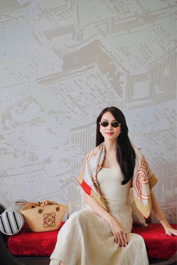 Một chiếc khăn lụa họa tiết được khoác tự nhiên trên vai, kính mắt dáng nhỏ đem lại nét hiện đại. Nếu bỏ những phụ kiện này, bộ đồ chỉ còn là sự kết hợp tương đối cơ bản giữa áo và chân váy màu kem. Chính chiếc khăn, kính và túi đã hoàn thiện câu chuyện thời trang.