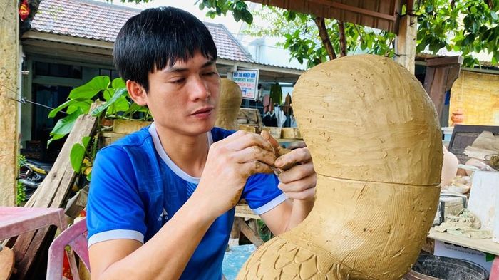 Nghệ nhân trẻ Lê Văn Nhật ở làng Thanh Hà chế tác linh vật rắn bằng gốm
