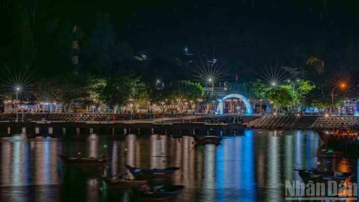 Cầu cảng Bãi Làng lung linh sắc màu dưới ánh đèn đêm. Những chiếc thuyền chài neo đậu yên bình trên mặt nước tĩnh lặng, phản chiếu ánh sáng tựa như một bức tranh thủy mặc hiện đại.