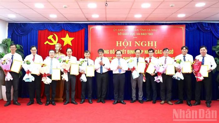 Phó Chủ tịch Ủy ban nhân dân tỉnh Cà Mau Nguyễn Minh Luân (thứ 6 từ phải qua) trao quyết định bổ nhiệm và tặng hoa các Hiệu trưởng Trường trung học phổ thông thuộc Sở Giáo dục và Đào tạo tỉnh. (Ảnh: HỮU TÙNG)