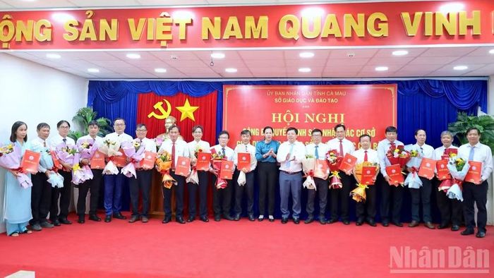 Giám đốc Sở Giáo dục và Đào tạo tỉnh Cà Mau Nguyễn Văn Nguyên (thứ 8 từ phải qua) trao quyết định sáp nhập 20 đơn vị, trường học trực thuộc sở. (Ảnh: HỮU TÙNG)