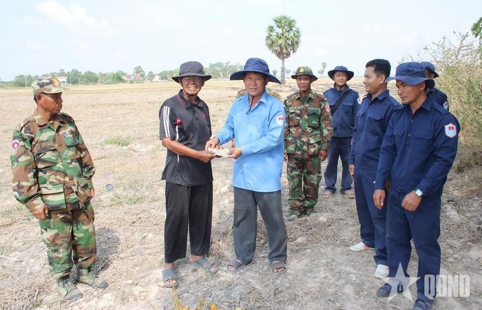 Thượng tá Võ Thành Dẫn (thứ ba, từ trái sang) trao tiền hỗ trợ người dân cung cấp thông tin về liệt sĩ tại huyện Ba Phnum, tỉnh Prey Veng (Campuchia). Ảnh: TRUNG THẮNG