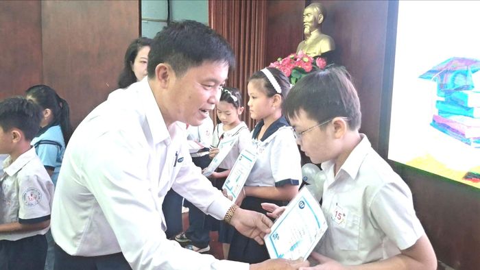 Ông Phan Công Trực, Giám đốc Tổ chức tài chính vi mô CEP, chi nhánh Tân Thới Hiệp, trao học bổng cho con công nhân. Ảnh: HỒNG ĐÀO