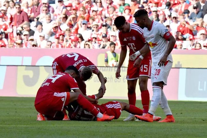 Sự cố đầu tiên xảy ra ở phút 83 trận gặp RB Leipzig. Chỉ khoảng 2 phút sau khi ghi bàn nâng tỷ số lên 3-1, Musiala có biểu hiện mất phương hướng, đứng không vững rồi từ từ khuỵu xuống sân. Tiền vệ Ismael Saibari kịp lao tới đỡ đồng đội, trước khi Joshua Kimmich cùng nhân viên y tế hỗ trợ. Ảnh: Reuters.