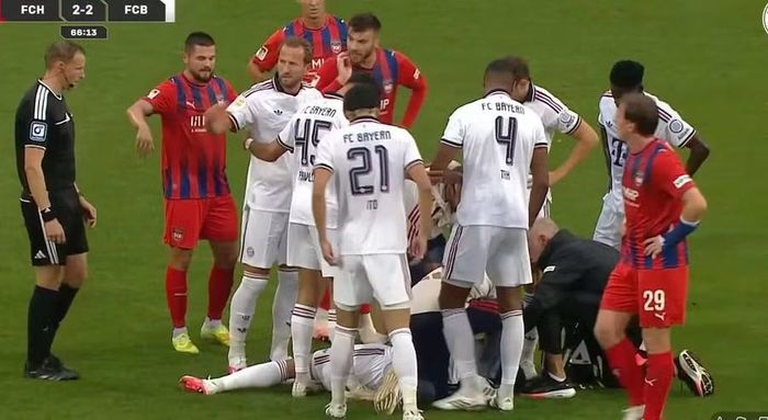 Chứng kiến đồng đội gặp vấn đề, tiền đạo Harry Kane lập tức yêu cầu cầu thủ hai đội đứng thành vòng tròn che chắn cho Musiala trong lúc được điều trị chăm sóc y tế. Tiền vệ Bayern Munich sau đó hồi phục, có thể đứng dậy và được bác sĩ dìu rời sân, nhưng 2 sự cố liên tiếp khiến tình trạng của anh trở thành mối quan tâm lớn. Ảnh: Getty Images.