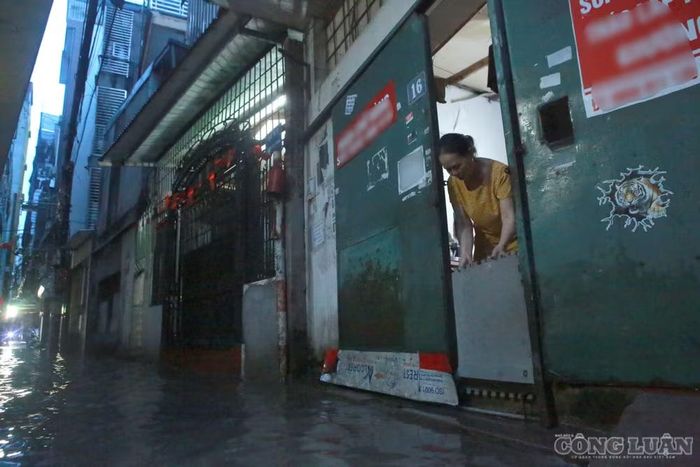 Bà Mai Thị Tân (66 tuổi) đang che chắn lại phần trước cửa để ngăn nước tràn vào nhà.