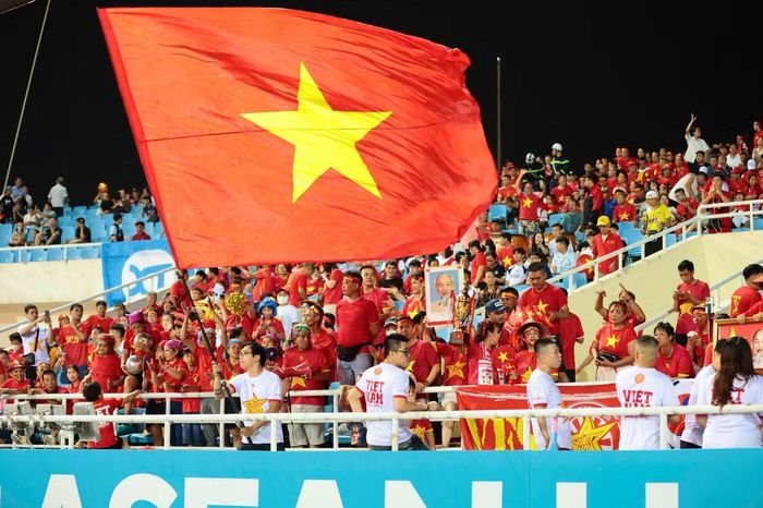 Gần sát giờ thi đấu, những lá cờ Tổ quốc tung bay, tạo nên một “biển đỏ” nổi bật trên khán đài. Tiếng hô “Việt Nam! Việt Nam!” liên tục vang lên khi các tuyển thủ bước ra sân khởi động.