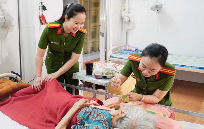 Thiếu tá Phạm Thị Thuỳ Dương đút từng muỗng cháo cho cụ già tại Trung tâm Dưỡng lão Mai Linh. Ảnh: Công an Vĩnh Long 