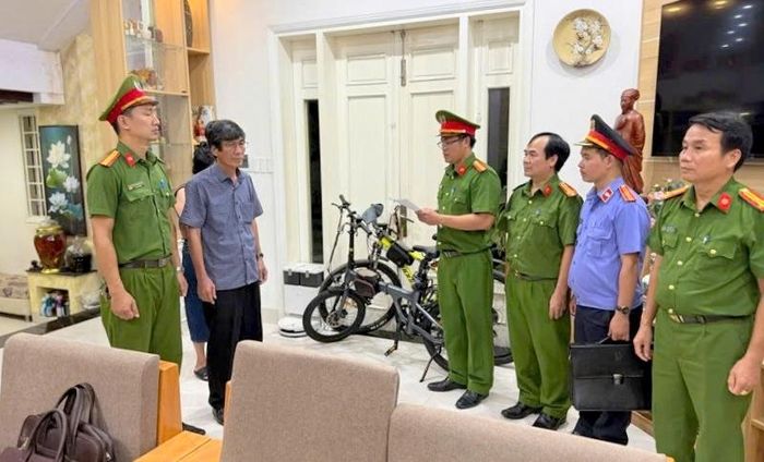 Tống đạt quyết định khởi tố bị can, lệnh bắt bị can để tạm giam đối với Hà Xuân Hậu (áo sơ mi xanh, đeo kính).