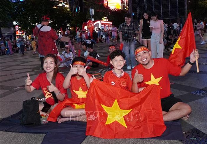 Gia đình anh Phạm Duy Quang (phường Bình Thạnh) cùng mang cờ Tổ quốc, hòa chung không khí cổ vũ đội tuyển Việt Nam tại phố đi bộ Nguyễn Huệ.