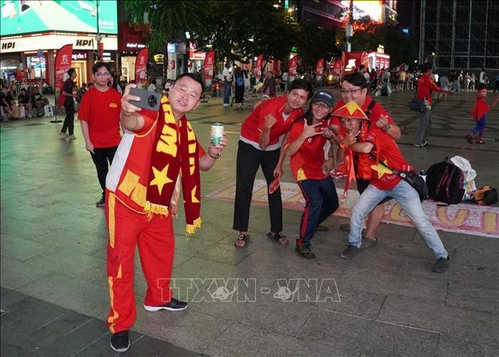 Người hâm mộ Thành phố Hồ Chí Minh chụp ảnh lưu niệm, hòa chung không khí cổ vũ đội tuyển Việt Nam tại phố đi bộ Nguyễn Huệ.