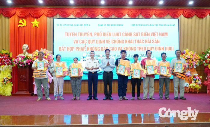 Đại diện Bộ Tư lệnh Vùng Cảnh sát biển 4 và lãnh đạo địa phương trao tặng cờ Tổ quốc, ảnh Bác Hồ và áo phao cho chủ tàu, thuyền trưởng tàu cá