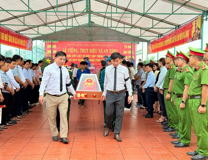 Lãnh đạo xã Duy Nghĩa trân trọng đưa linh cữu hài cốt liệt sĩ đi an táng. Ảnh: TUYẾT MAI