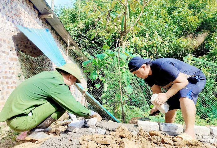 Cán bộ Công an xã Nghĩa Tá giúp người dân địa phương xóa nhà tạm, nhà dột nát.