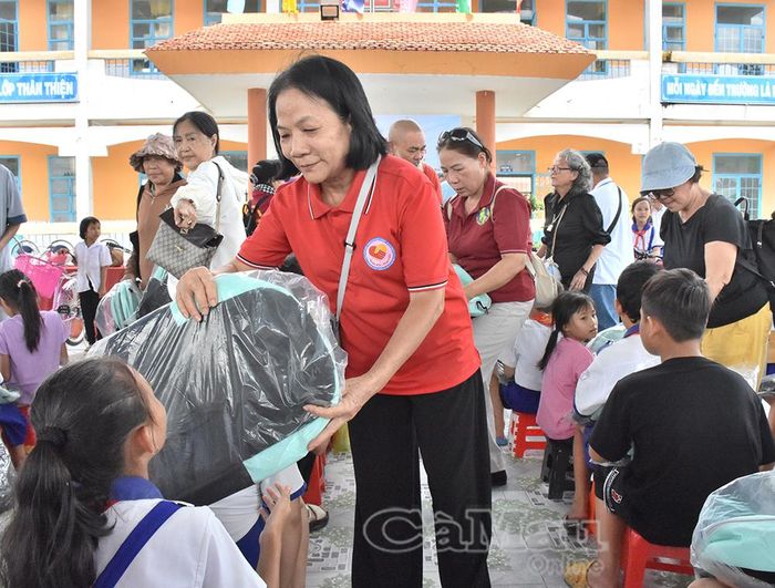 Thành viên đoàn từ thiện trao tặng cặp cho học sinh Trường Tiểu học Lương Thế Vinh, ấp Xóm Tre, xã Ninh Quới.