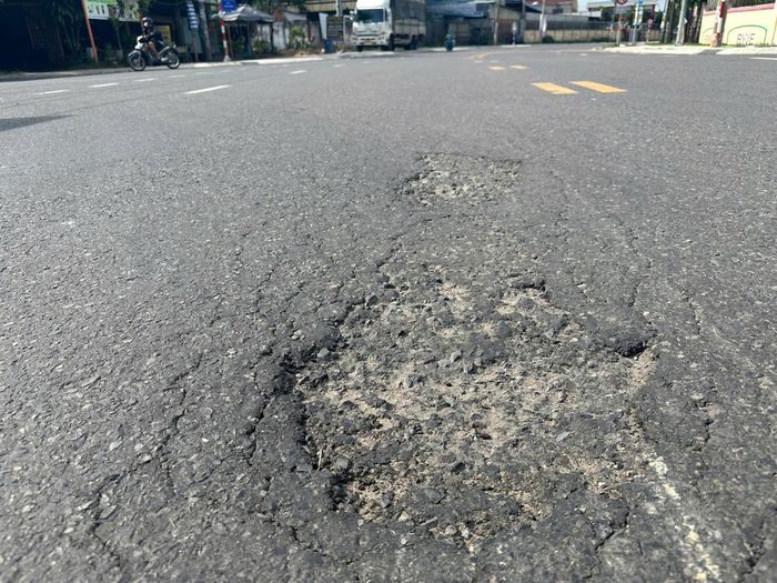 Mặt đường bị bong tróc tạo thành hố.