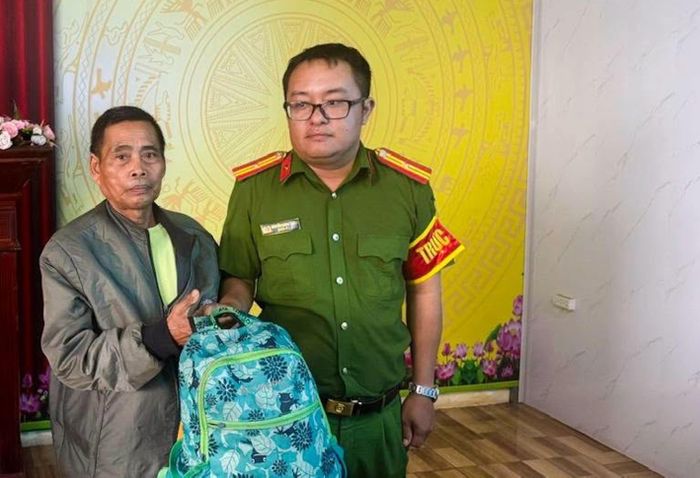 Cán bộ Công an xã Hướng Phùng trao trả chiếc ba lô chứa tiền và đồ dùng cá nhân cho ông Hồ Văn Hoà. (Ảnh: Công an xã Hướng Phùng)
