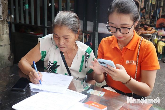 Bà Nguyễn Thị Lân tiểu thương chợ Kiến Hưng được hướng dẫn mở tài khoản thanh toán và sử dụng ngân hàng số. Ảnh: Tuấn Điệp