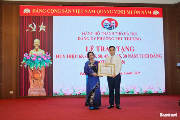 Đồng chí Nguyễn Quốc Hà, Bí thư Đảng ủy, Chủ tịch HĐND phường Phú Thượng trao Huy hiệu Đảng tặng đảng viên. Ảnh: Cao Kỳ