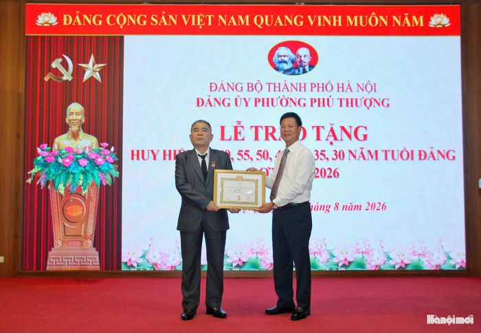 Đồng chí Đỗ Đình Sơn, Phó Bí thư Đảng ủy, Chủ tịch UBND phường Phú Thượng trao Huy hiệu Đảng tặng đảng viên. Ảnh: Cao Kỳ