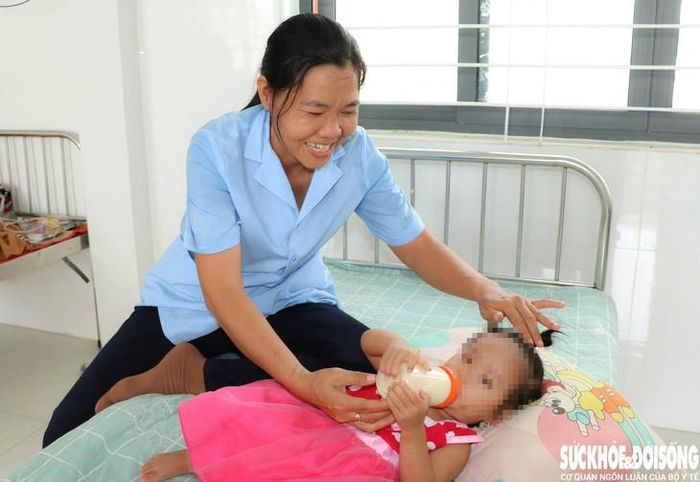 Bảo mẫu Lê Thị Bình Minh vui vẻ chăm sóc bé Dâu. Ảnh: Duy Ngọc.