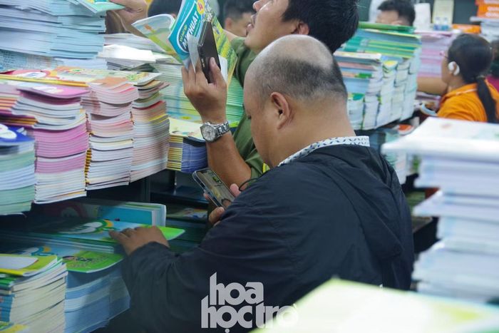 Nhiều phụ huynh cẩn thận ghi lại những tựa sách cần mua, đối chiếu hình ảnh và kiểm tra thật kỹ trước khi thanh toán để đảm bảo mua đúng sách cho con. Ảnh: Kim Cương.