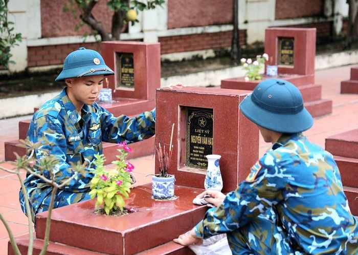 Các chiến sĩ của Trung đoàn 260 và lực lượng dân quân xã Đan Phượng lau dọn mộ liệt sĩ