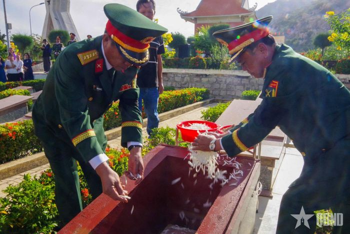  Các đại biểu thả hoa vào các huyệt chôn cất hài cốt liệt sĩ.