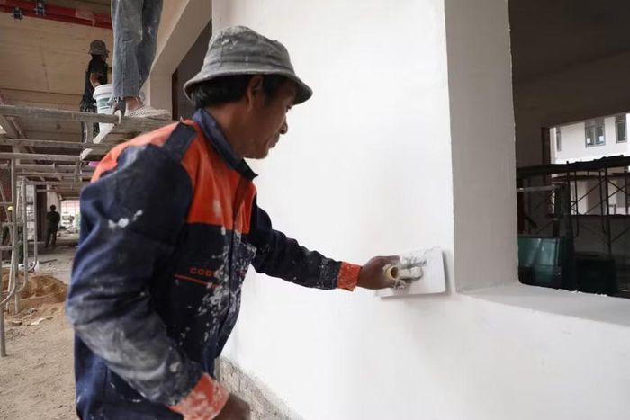 Công nhân đang trít tường phòng học.