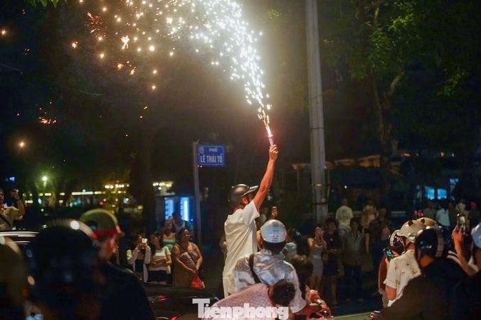 Một số cổ động viên đốt pháo sáng giữa đám đông, khiến khu vực trung tâm Hà Nội rực sáng trong đêm.