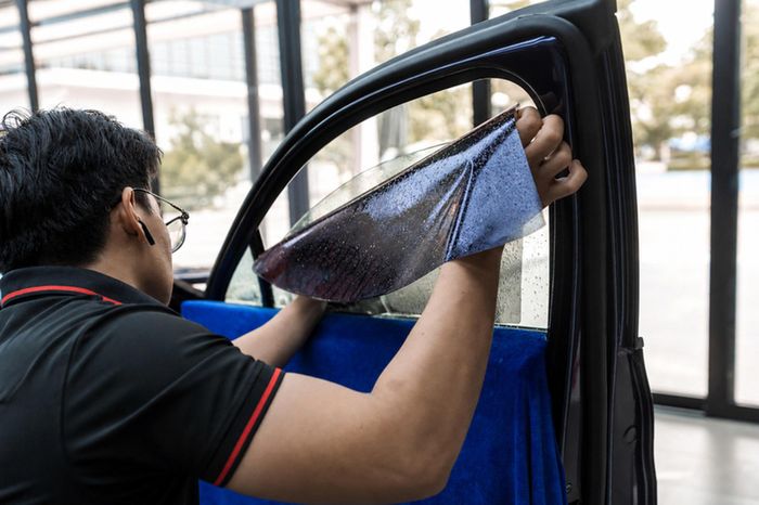 Kỹ thuật viên định hình và căn chỉnh phim trên kính trong quá trình thi công