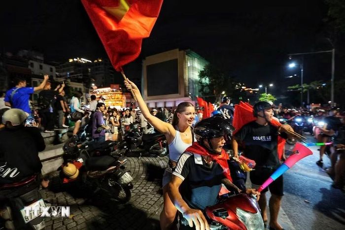 Du khách nước ngoài hòa cùng niềm vui chiến thắng của đội tuyển Việt Nam. (Ảnh: Phạm Tuấn Anh/TTXVN)