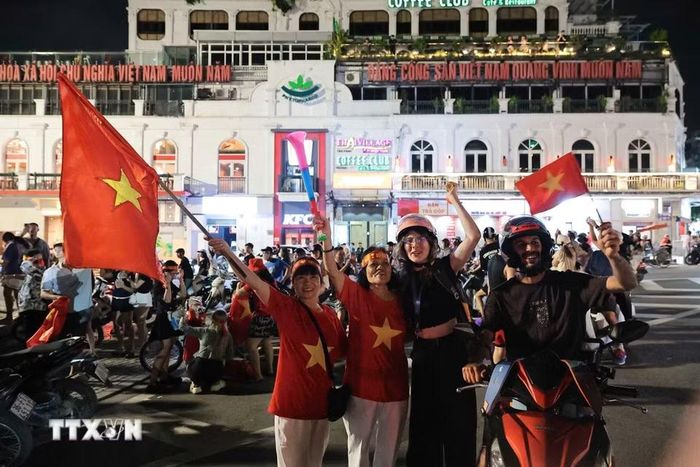 Du khách nước ngoài hòa cùng niềm vui chiến thắng của đội tuyển Việt Nam. (Ảnh: Phạm Tuấn Anh/TTXVN)
