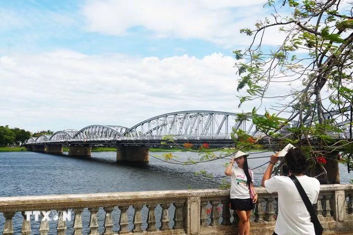 Du khách chụp ảnh bên cầu Trường Tiền. (Ảnh: Nguyên Lý/TTXVN)