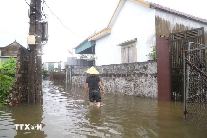 Nước ngập sâu ngang đầu gối, người dân phải lội bộ. (Ảnh: Xuân Tiến/TTXVN)