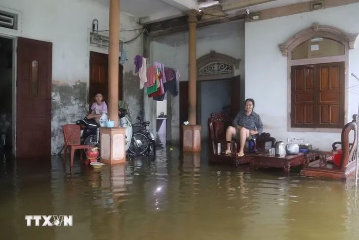 Trước tình trạng bị nước bủa vây, ngập sâu, người lớn tuổi và trẻ em phải ngồi trên ghế cao để tránh ướt, xe máy, xe đạp và các vật dụng khác phải kê lên chỗ cao. (Ảnh: Xuân Tiến/TTXVN)