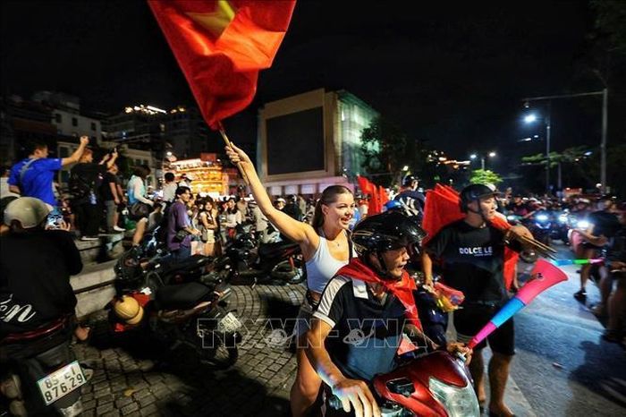 Du khách nước ngoài hòa cùng niềm vui chiến thắng của đội tuyển Việt Nam. Ảnh: Phạm Tuấn Anh/TTXVN
