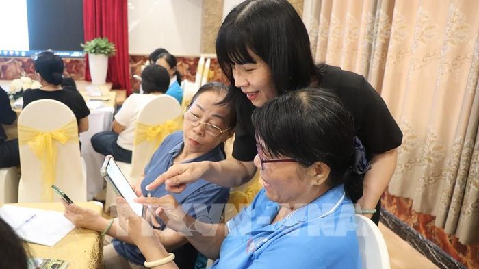 Đại diện Hội Liên hiệp phụ nữ thành phố hỗ trợ học viên thực hành ứng dụng AI trên điện thoại. Ảnh: Nguyễn Hằng - TTXVN 