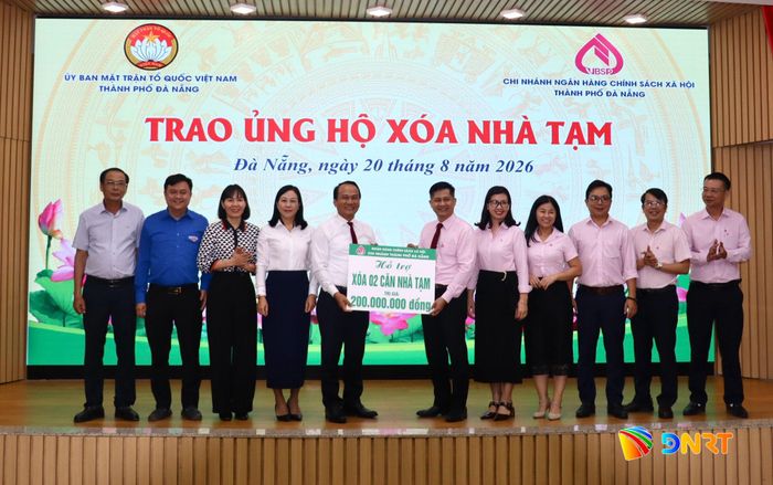 Lãnh đạo Ủy ban MTTQ Việt Nam thành phố tiếp nhận bảng tượng trưng kinh phí xóa 2 căn nhà tạm do đại diện Ngân hàng Chính sách xã hội thành phố trao tại hội nghị. Ảnh: QUỐC TUẤN