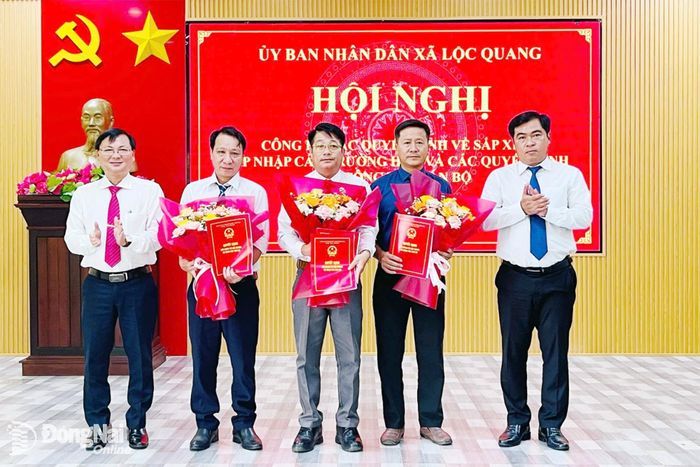 Lãnh đạo xã Lộc Quang trao quyết định và tặng hoa chúc mừng Ban giám hiệu Trường tiểu học Lộc Quang. Ảnh: Thái Chung